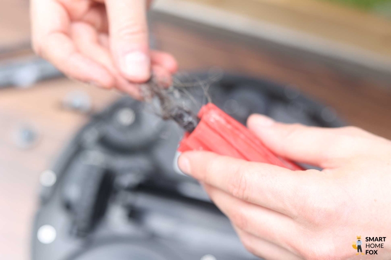 Haare werden aus der Hauptbürste mit Hilfe einer Schere entfernt.
